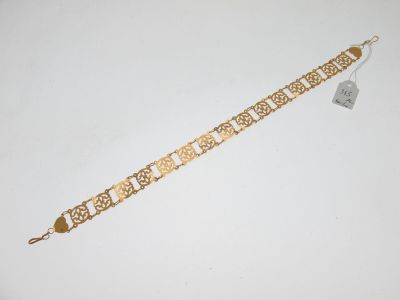 gros plan d'un bracelet en or sur une surface blanche