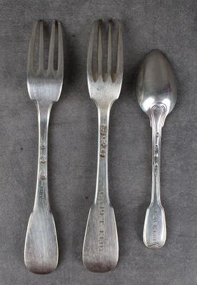 trois cuillères en argent et une fourchette posées sur un plateau gris