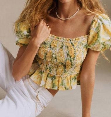 the woman is sitting on the floor wearing white pants and a yellow top