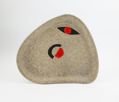 a stone with a face on it sitting on a white surface
