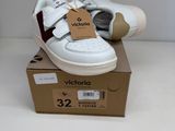 des chaussures de bébé blanches et rouges posées sur une boîte, sur une surface blanche