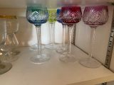 Plusieurs verres à vin sont alignés sur une étagère dans une cuisine.
