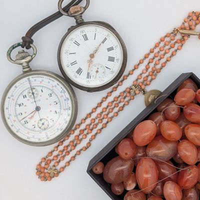 une boîte de perles et une montre de poche posées sur une table