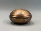 une boîte ancienne en laiton avec un couvercle bombé, posée sur une surface grise