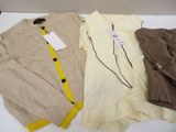 three pairs of sweaters and pants sitting on a white table