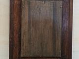 an old wooden mirror hanging on a wall with a metal hook