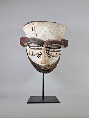 Rare masque expressif en bois et pigments noirs et blancs.