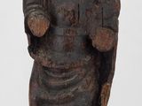 une vieille statue en bois représentant un homme tenant un bouclier et un bouclier