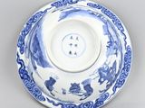 blue and white plate with a design of people on it