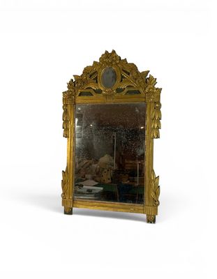 un miroir avec un cadre doré et une horloge dessus