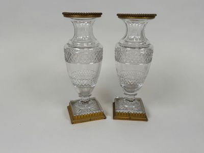 une paire de vases en cristal taillé reposant sur des socles en bois, sur fond blanc