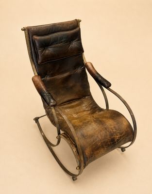 fauteuil à bascule en cuir marron posé sur une surface blanche