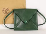 sac à main en cuir vert, orné d'un bouton vert sur le devant et d'un compartiment marron à l'arrière