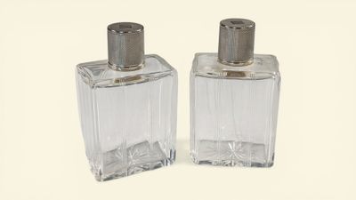 two bottles of perfume sitting next to each other on a white surface