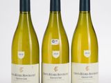 trois bouteilles de vin blanc posées l'une à côté de l'autre sur une surface blanche