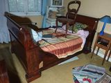 un lit qui se trouve dans une chambre où il y a beaucoup d'objets par terre