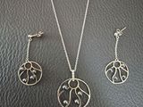 a close up of a necklace and earrings on a leather surface