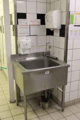 un lavabo dans des toilettes publiques, avec un distributeur de papier accroché au mur