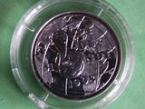 a silver coin in a plastic container on a green surface