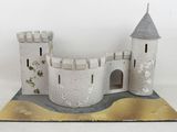 une petite maquette de château posée sur une surface blanche