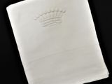 serviette blanche sur laquelle est brodée une couronne sur fond noir