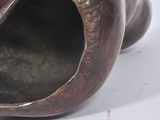 bronze sculpture of a cat curled up on its back on a white surface