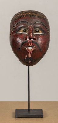 a close up of a wooden mask on a stand on a table