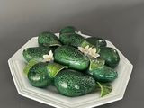 some green cucumbers are on a white plate on a gray surface
