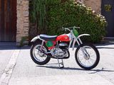 a red and green dirt bike parked in front of a stone building