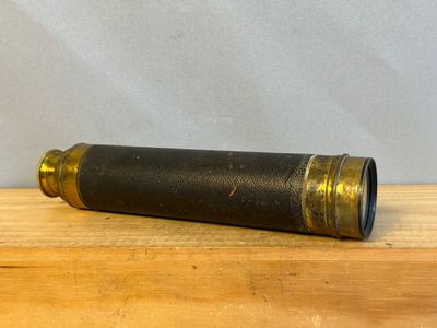 un vieux télescope noir et en laiton posé sur une table en bois