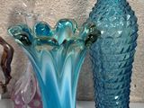 three glass vases sitting on a shelf next to each other