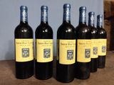 six bottles of wine are lined up on a wooden table