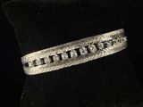 un gros plan d'un bracelet en argent posé sur un anneau en velours noir