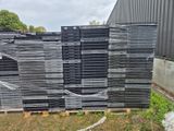 une pile de bâches en plastique noir posée sur une palette en bois