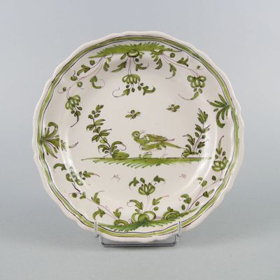 une assiette ancienne verte et blanche sur laquelle est représenté un oiseau