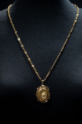 a gold necklace with a circular pendant on a mannequin neck