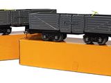 deux petits trains posés sur des cartons, sur une table