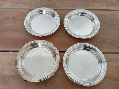 four silverplated dishes on a wooden table with a wooden table top