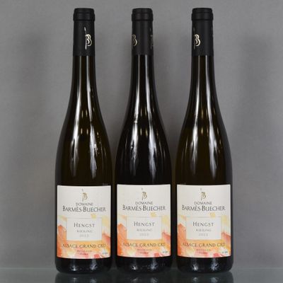 trois bouteilles de vin sont posées sur une table devant un fond gris