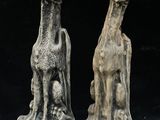 two statues of animals that are sitting on a black surface