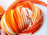 a person holding a yarn ball with orange and white stripes