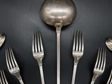 several forks and spoons are arranged in a circle on a black surface
