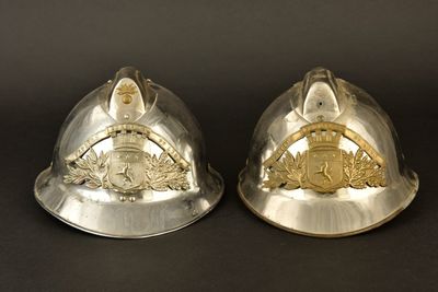 une paire de casques en argent ornés d'emblèmes dorés sur fond noir
