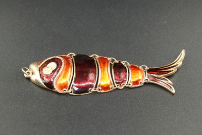 un gros plan d'une broche en forme de poisson posée sur une surface noire