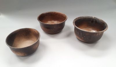 three brown bowls sitting on top of a white table next to each other