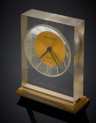 a glass clock with a yellow face on a black surface