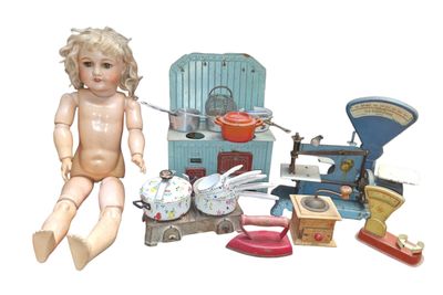 une poupée assise par terre à côté d'un tas de vieux jouets