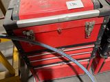 une boîte à outils rouge à laquelle est fixé un tuyau