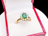 a green stone ring in a red box on a white plate