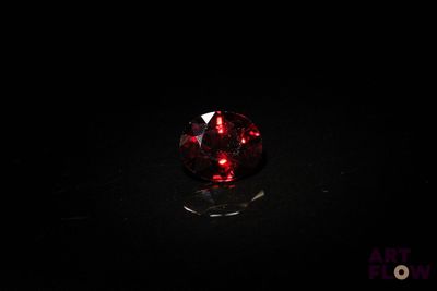 un gros plan d'une boule de verre rouge posée sur une surface noire